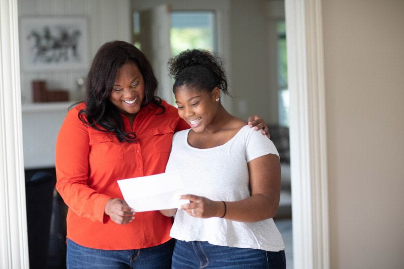 Working mom and daughter looking at college acceptance letter
