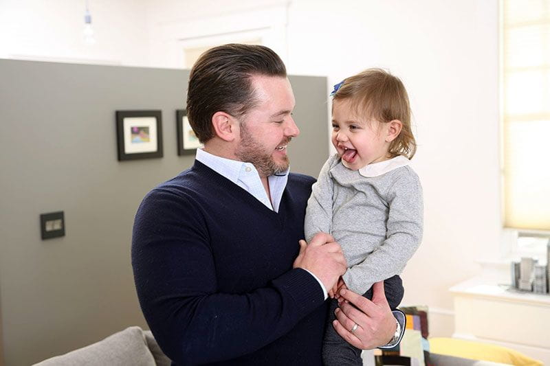 Working dad holding his preschool aged daughter