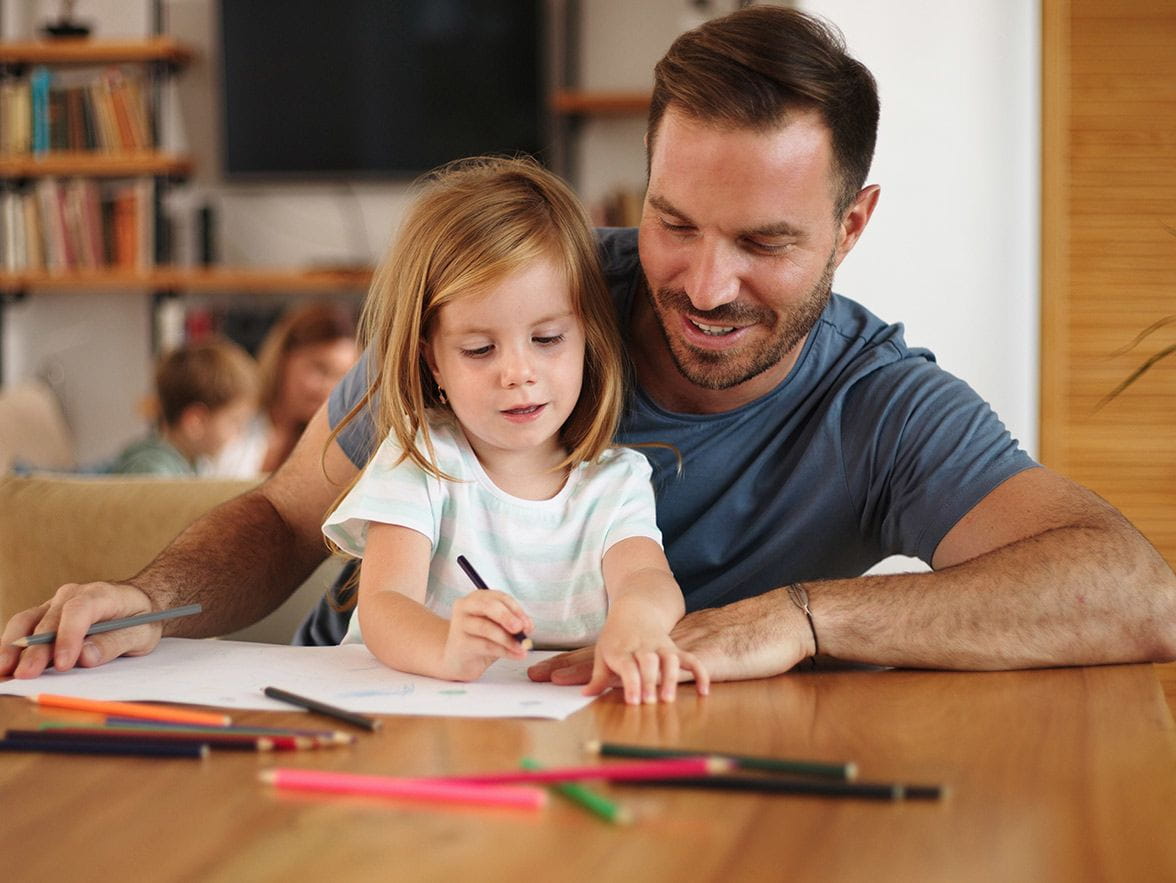 Father sitting at a table with daughter in his lap
