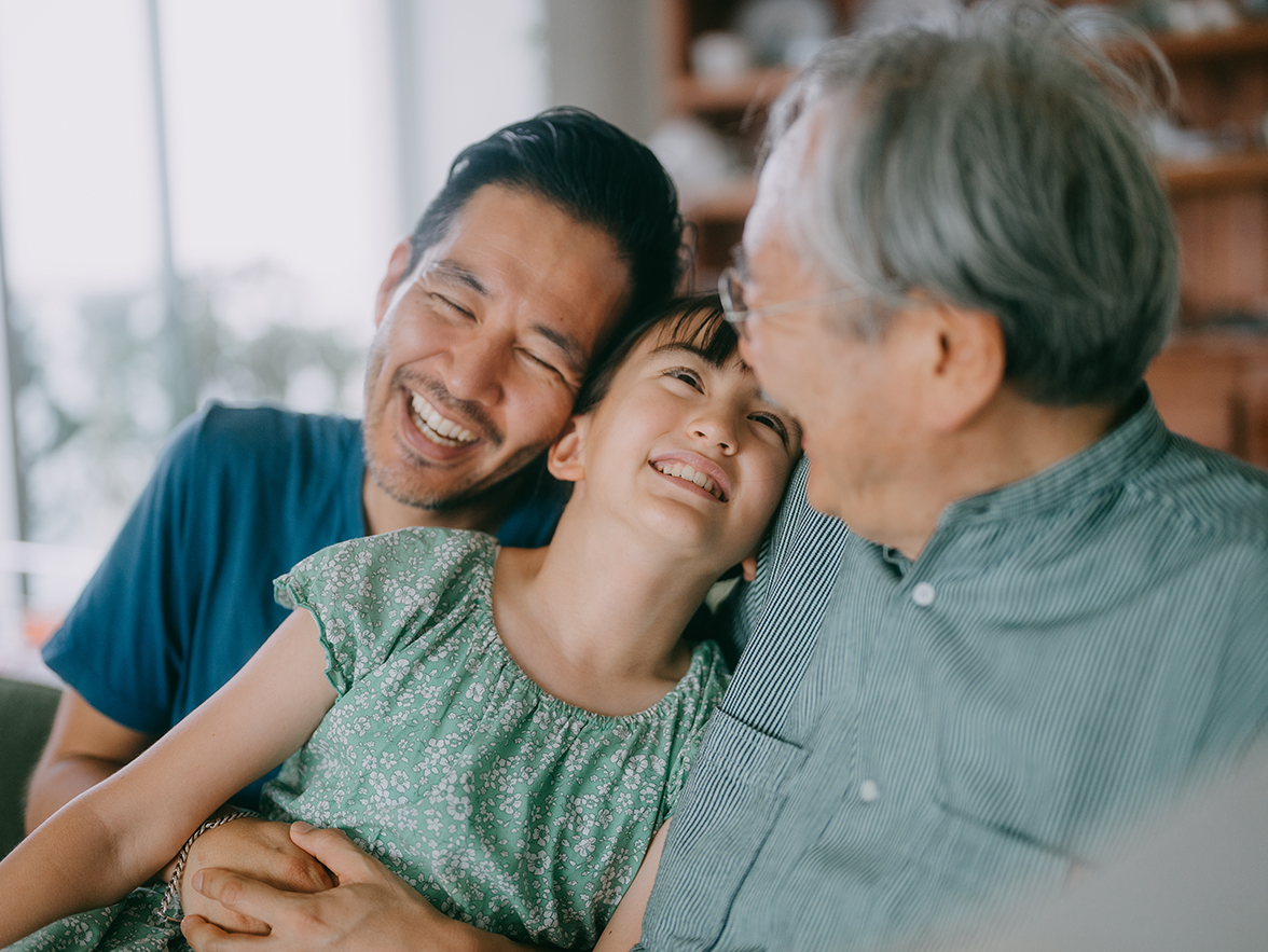 Man sitting with his daughter and his father, all smiling