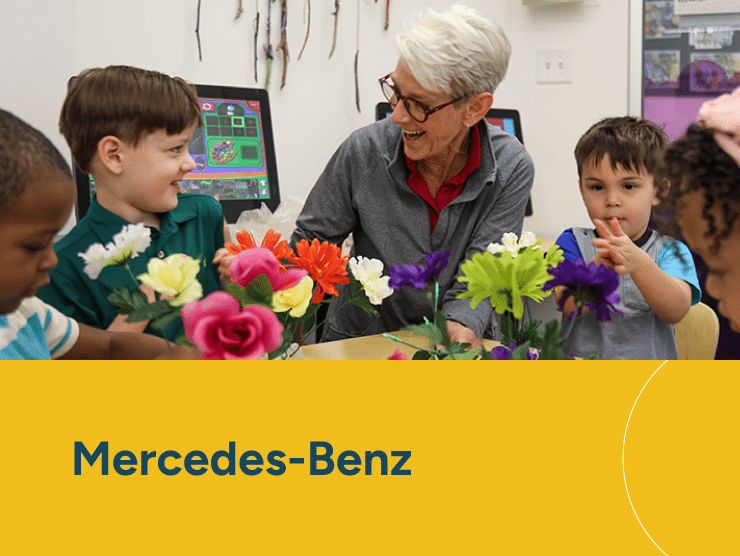 Mercedes-Benz with a caregiver with a group of students at a table
