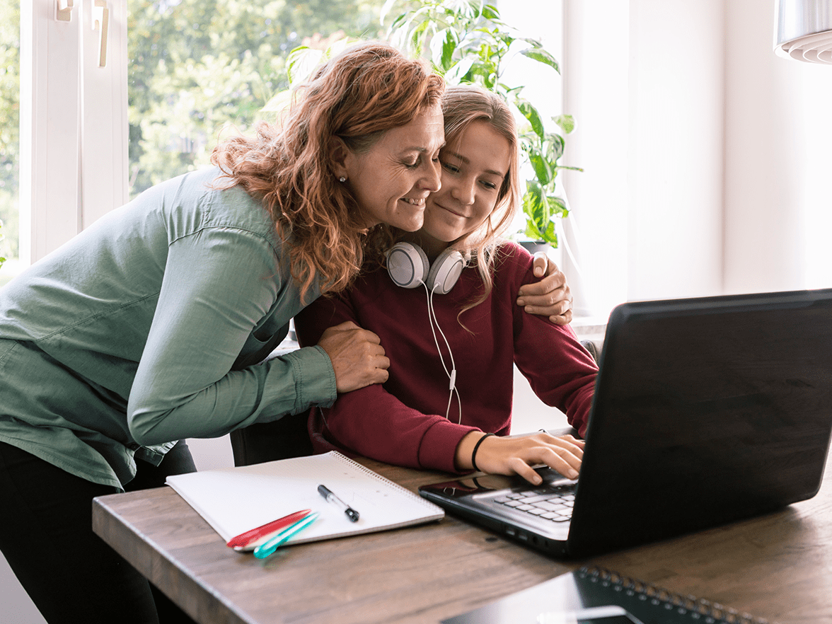 Mother and daughter looking at laptop and hugging