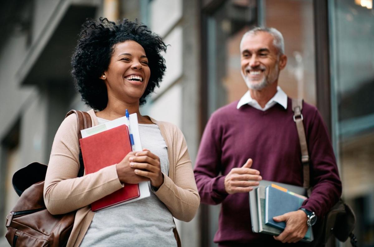 adult students carrying books and chatting