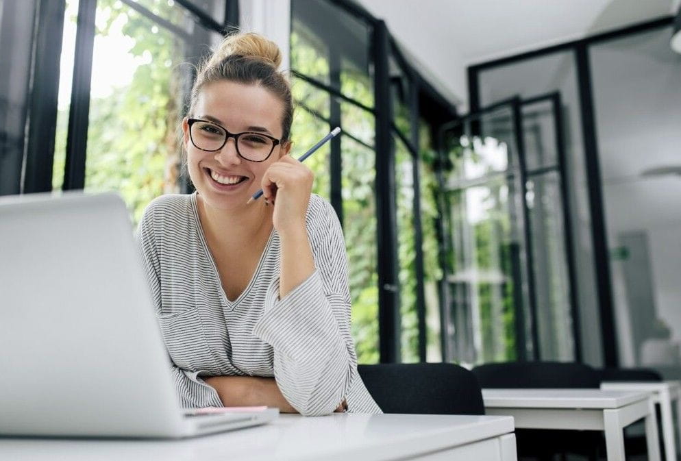 woman taking notes while working on laptop