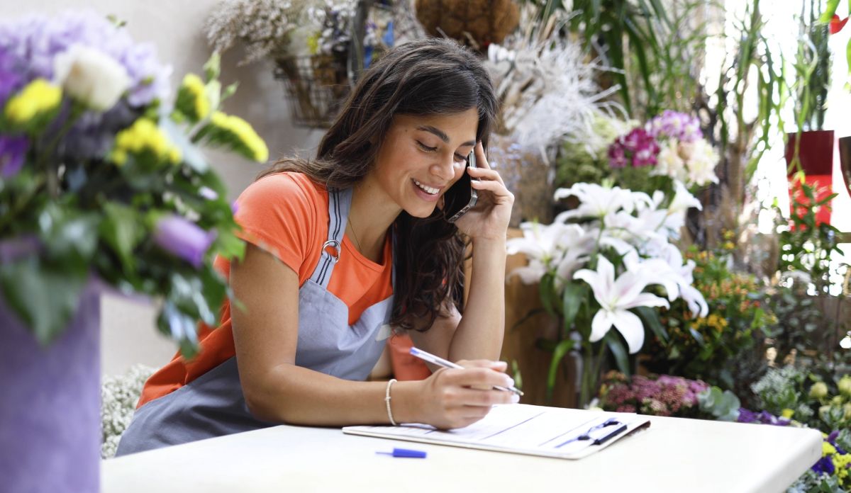 woman taking notes while talking on the phone