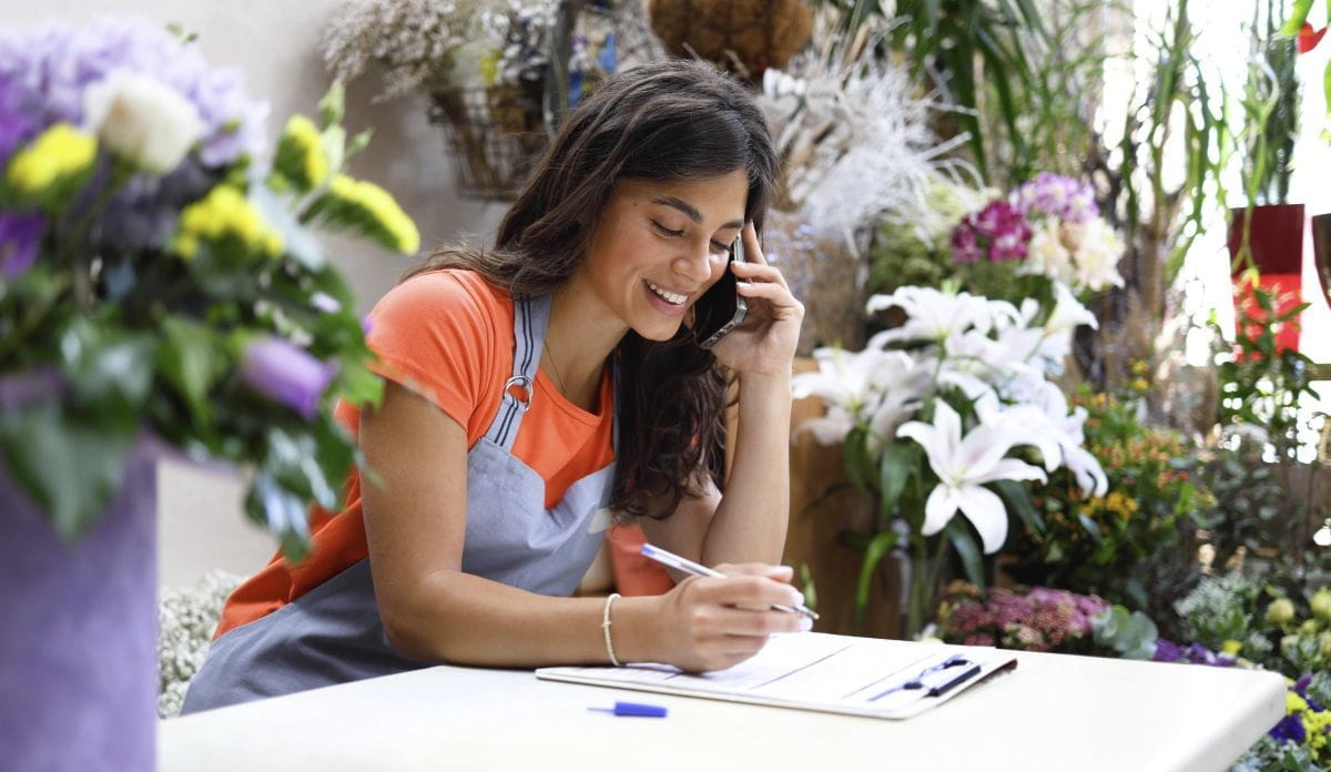 woman taking notes while talking on the phone