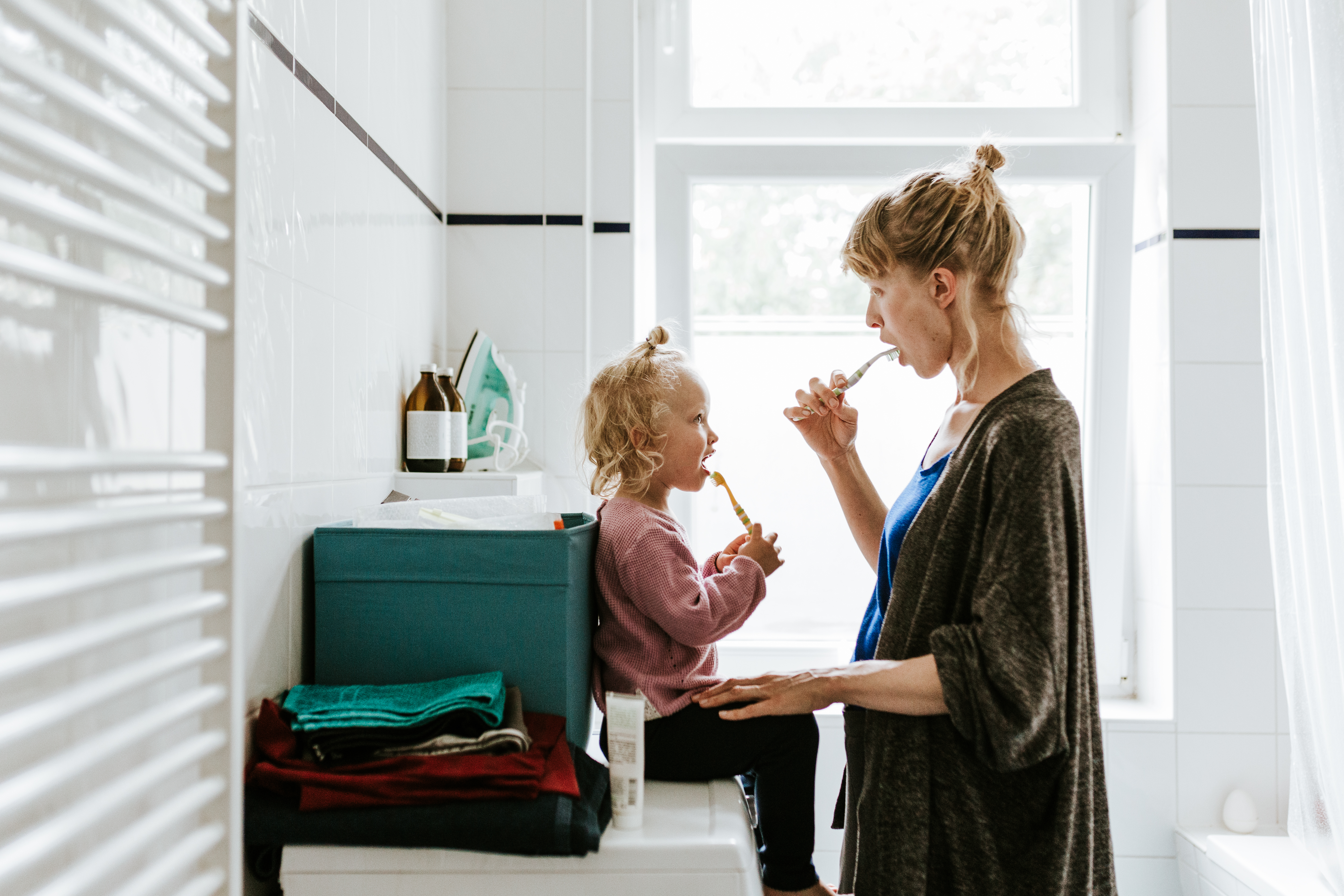 mother brushing teeth with daughter