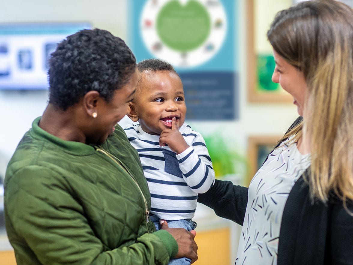 Caregiver and parent smiling at child