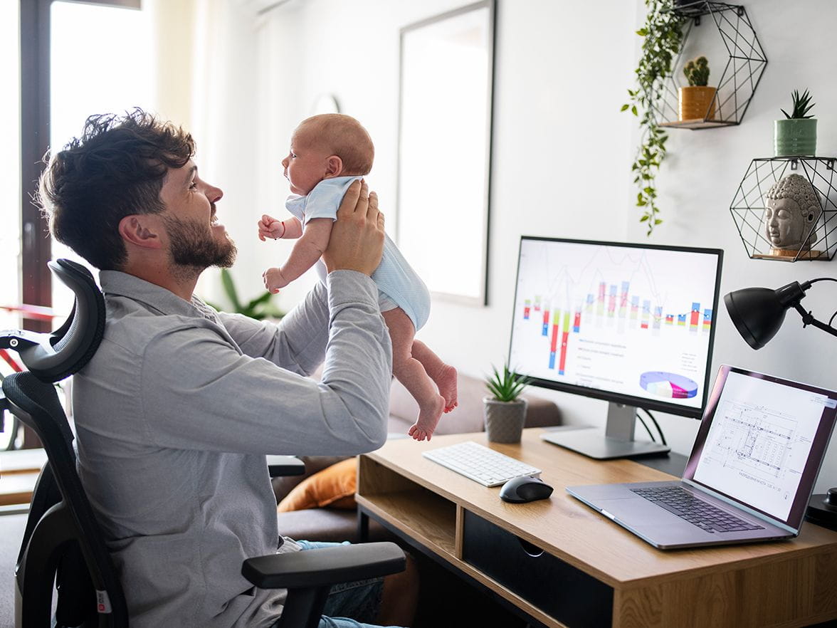 Father sitting at a desk holding baby