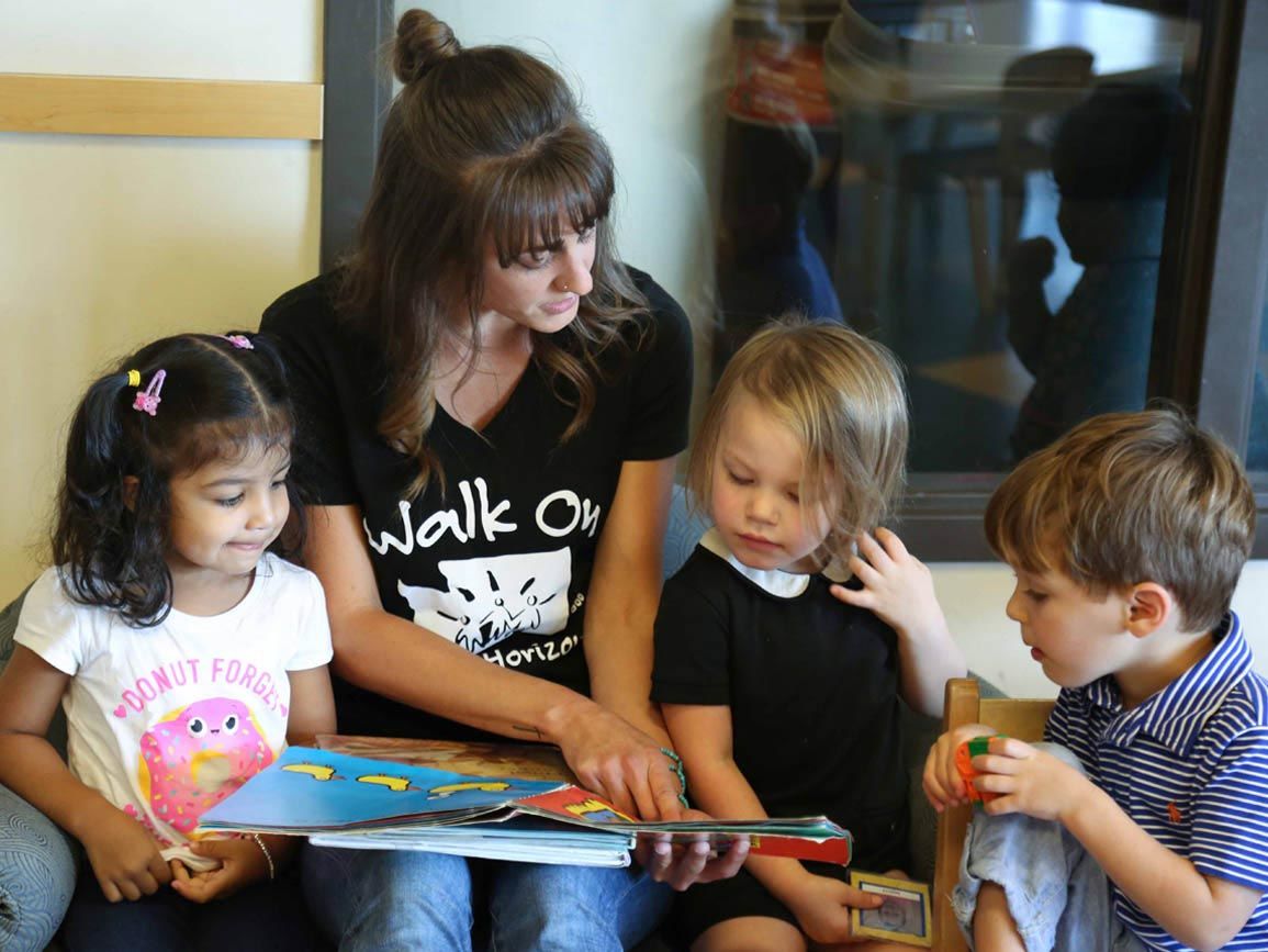 A group of children reading with their child care teacher