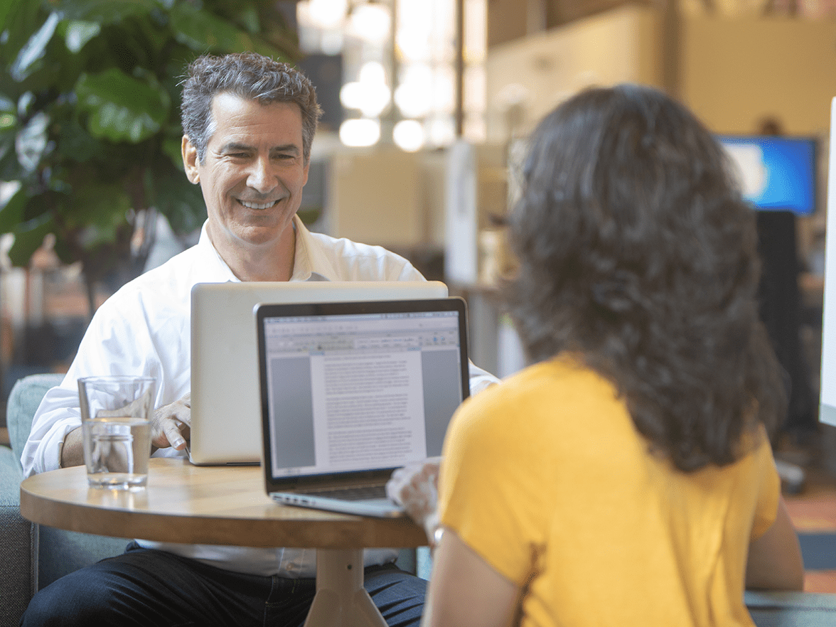 A man and woman using laptops in a cafe. 