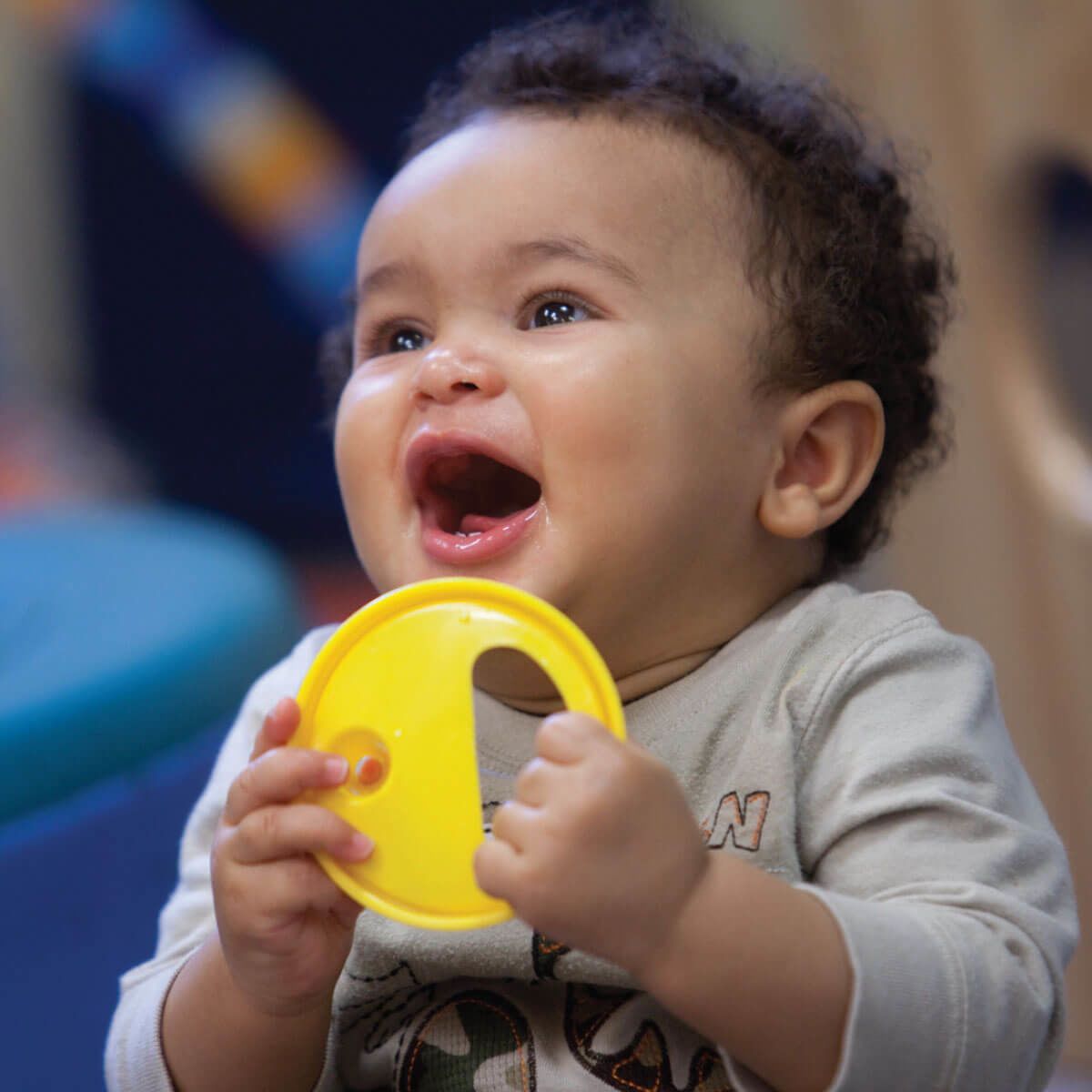 Infant boy holding a toy and smiling