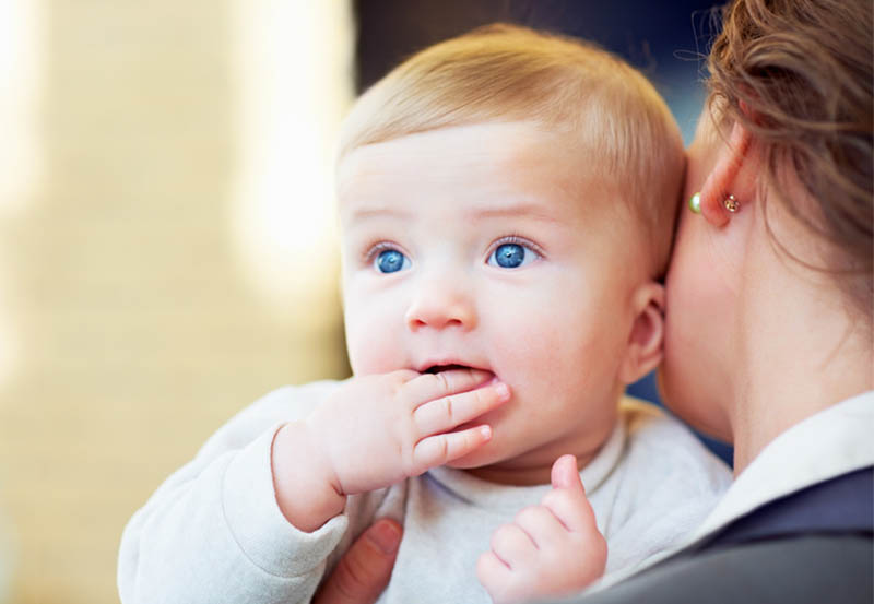 Baby smiling over mom's shoulder