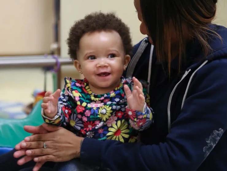 Young baby having fun at daycare on teachers lap