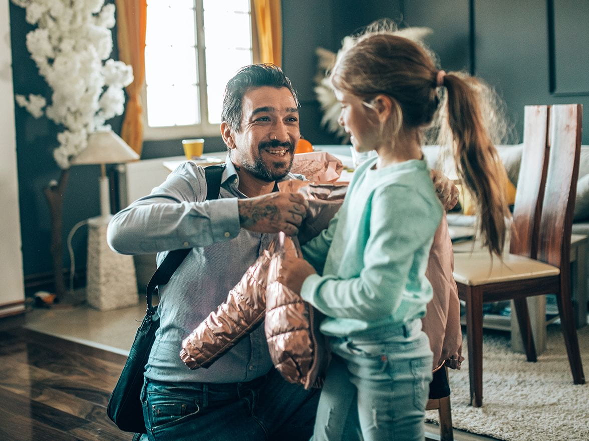 father putting jacket on daughter