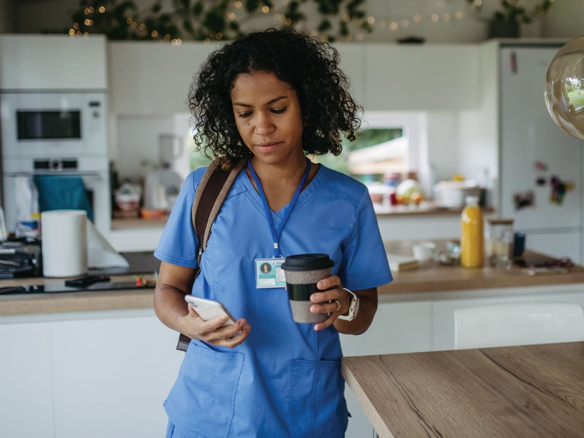 Healthcare worker in scrubs looking at phone