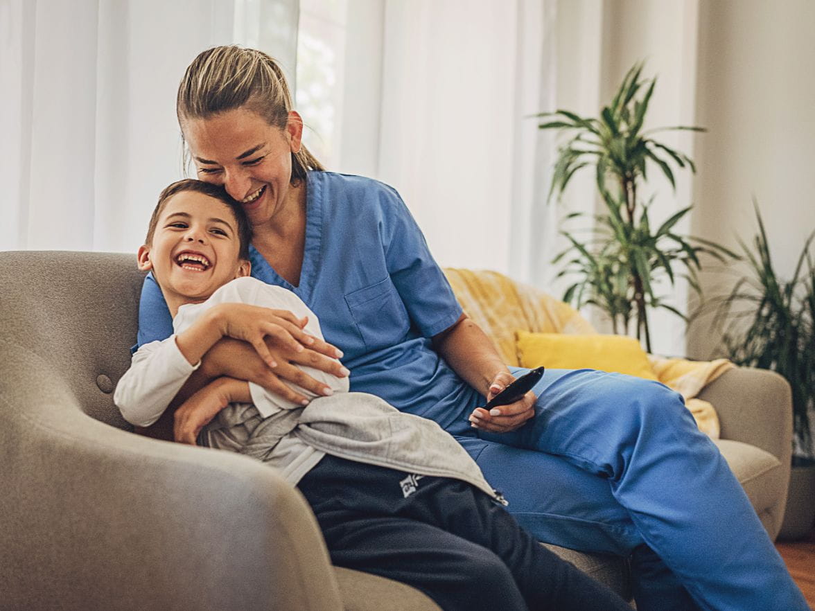 Mother in scrubs sitting in chair with son smiling