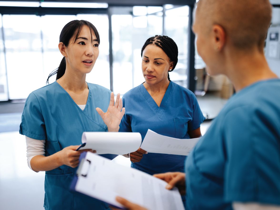 Three healthcare workers having a discussion, all in scrubs