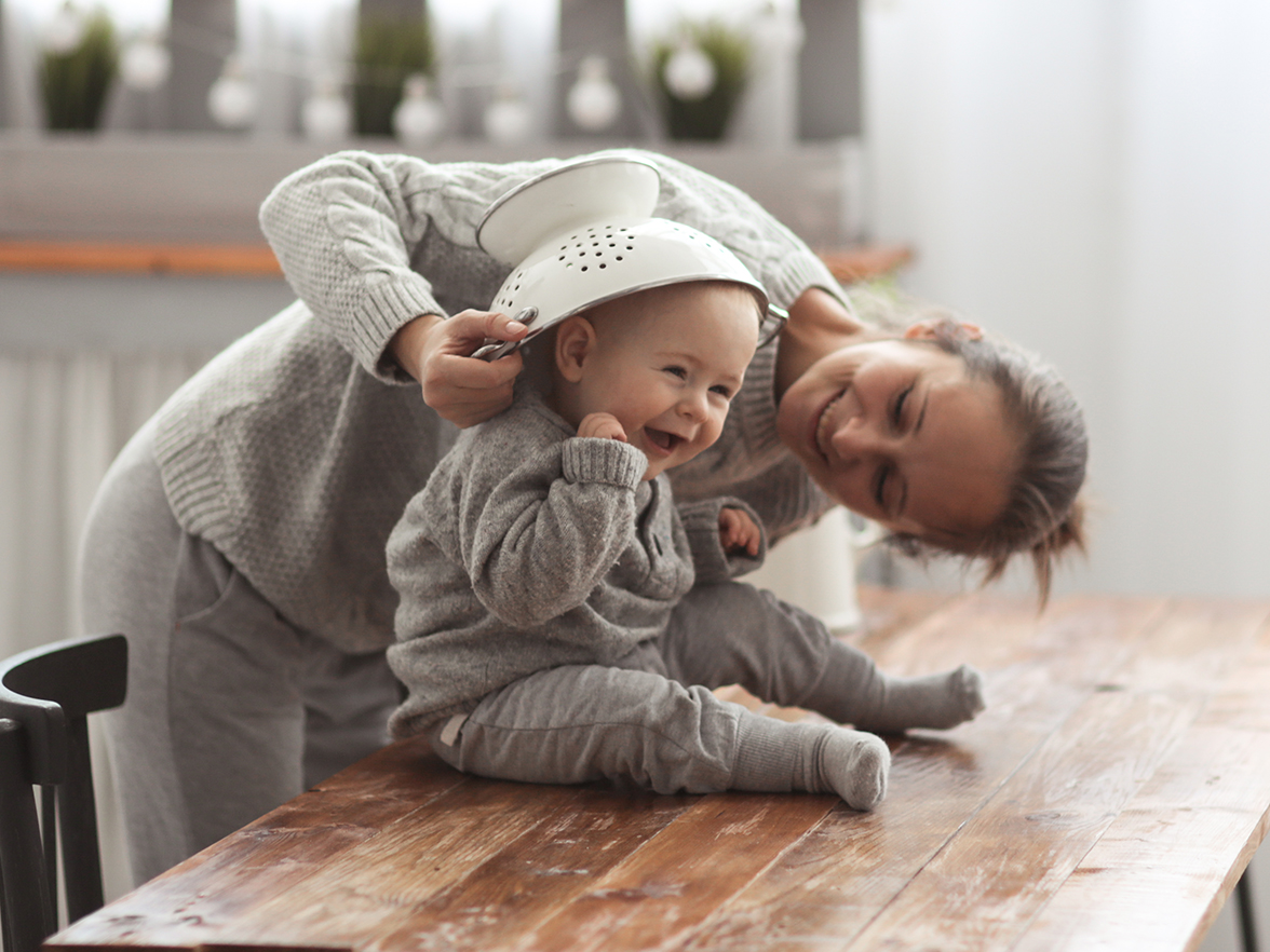 A woman playing with a child in a kitchen