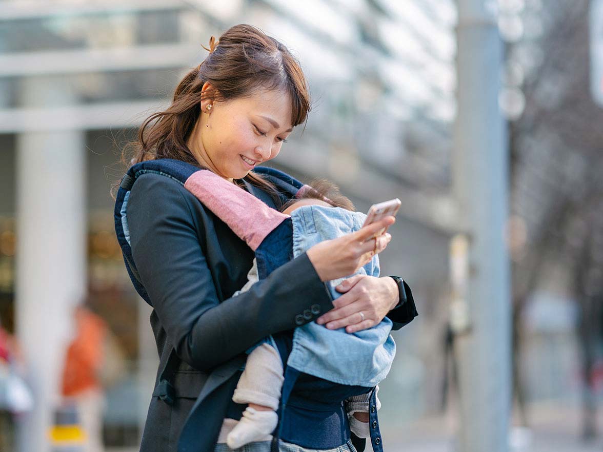 Bright Horizons Modern Family Index Busy Woman with Baby in Sling In City