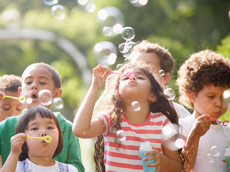 Children playing outside blowing bubbles