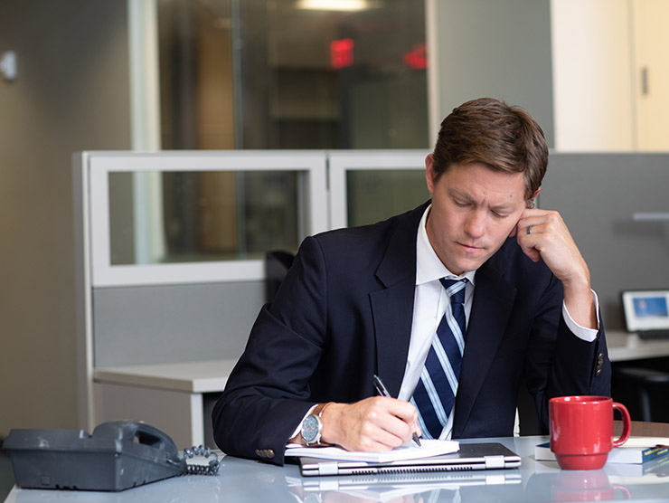 Male employee working at desk with cup of coffee