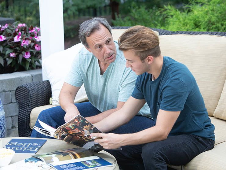 Father and teenage son reviewing college brochures