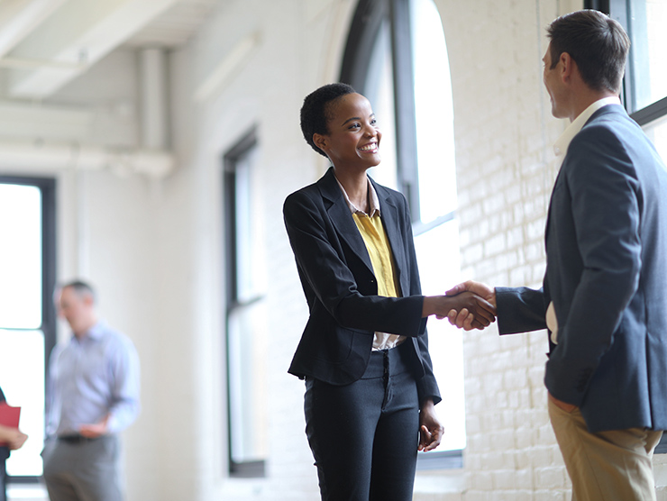 Professionally dressed woman and man shaking hands