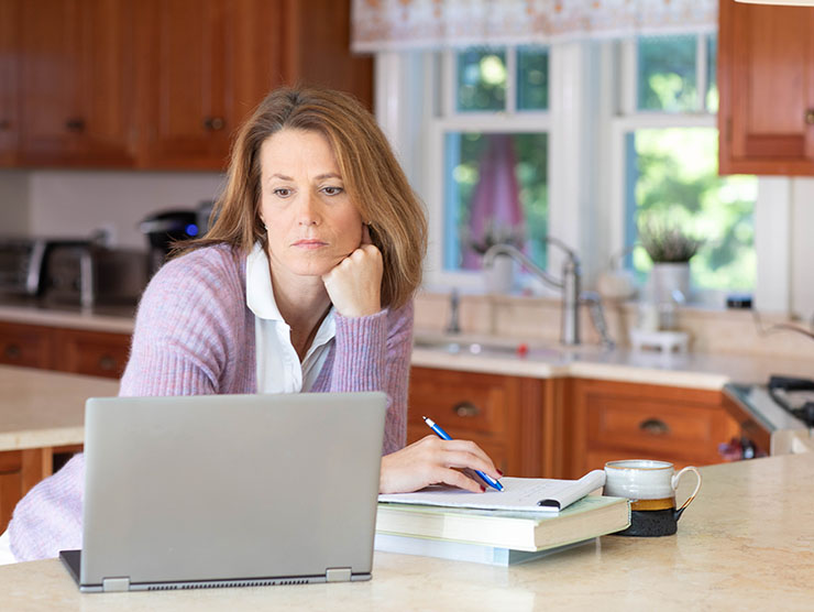 Woman working at laptop in her home kitchen