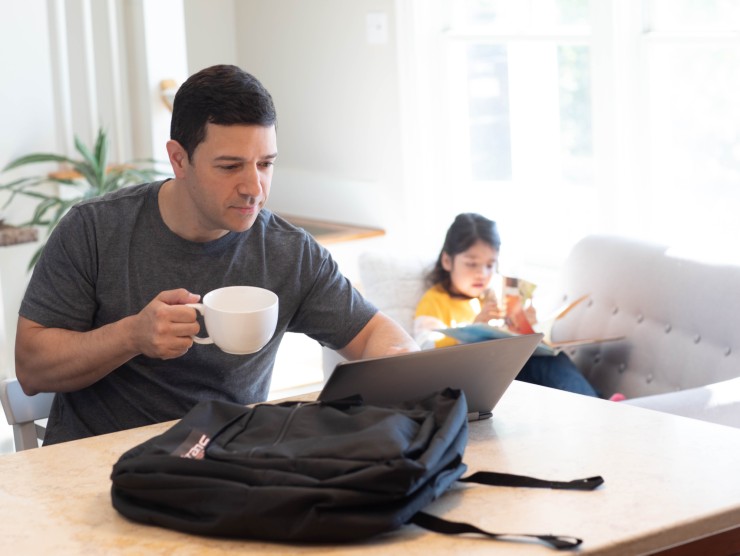 father working with daughter in background