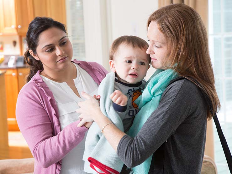 Caregiver taking child from mother, who is leaving for work