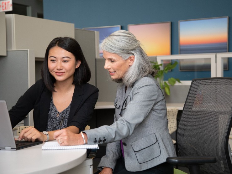 cross generational coworkers sitting with laptop 