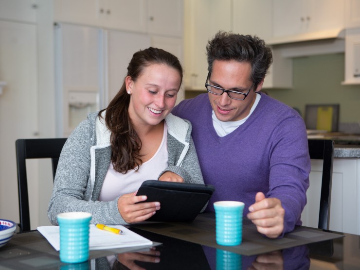 daughter and father sitting at table looking at ipad