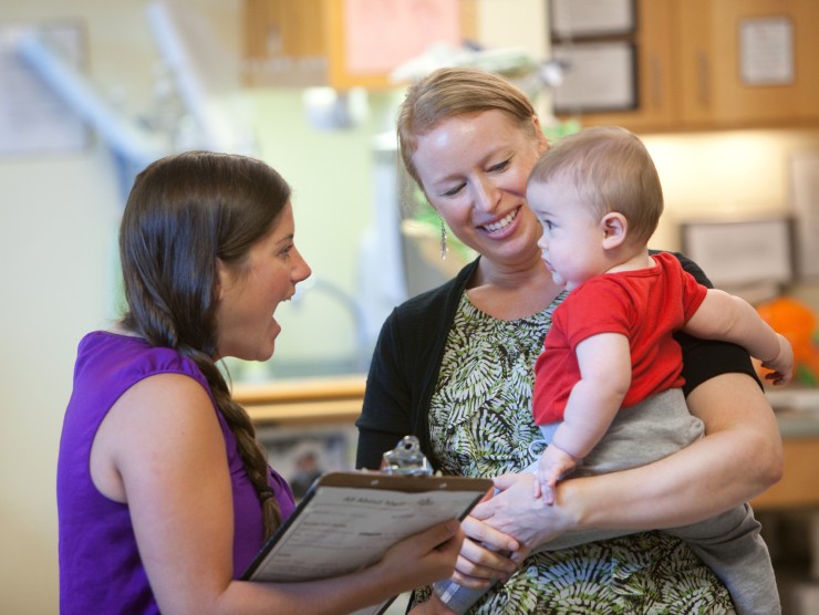 mother dropping off baby to teacher 