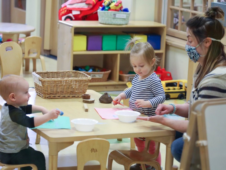 teacher sitting at table with children 