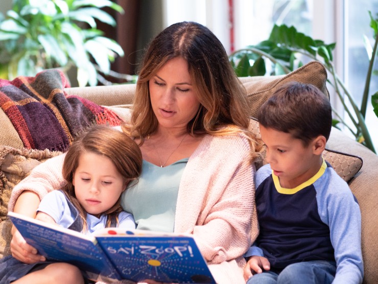 mother reading a book to her children 