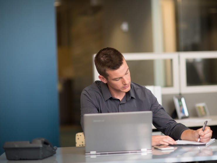 man sitting at table with laptop and notebook 