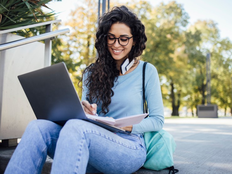 adult learner sitting on steps with laptop