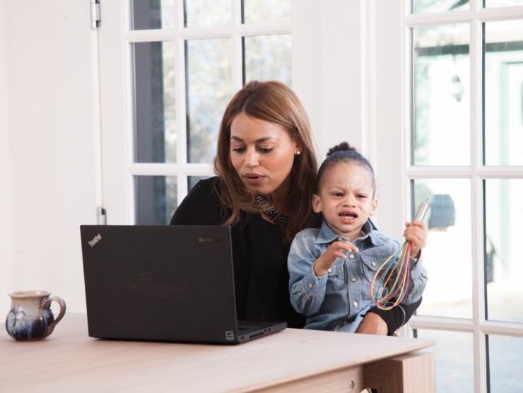 Mom working on her laptop while holding her preschooler