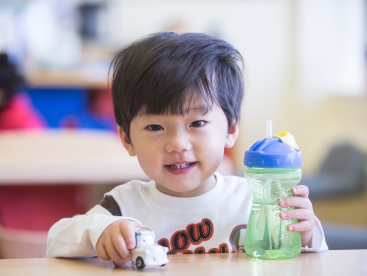 child sitting at table with toy truck 