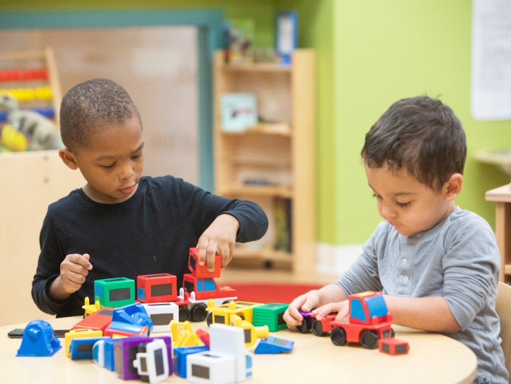 two children playing at table with toys