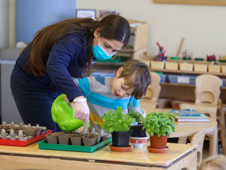 teacher with child watering plants 