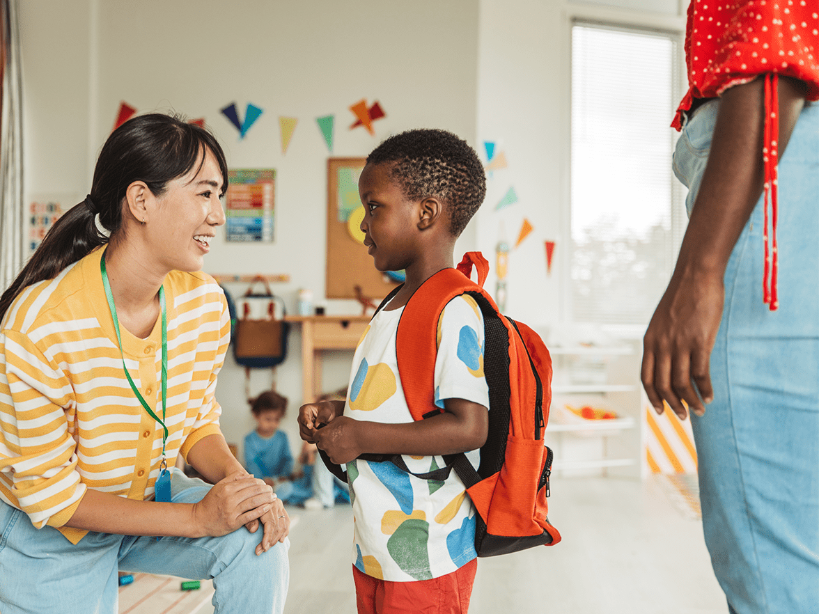 Caregiver kneeling to greet a child at a center