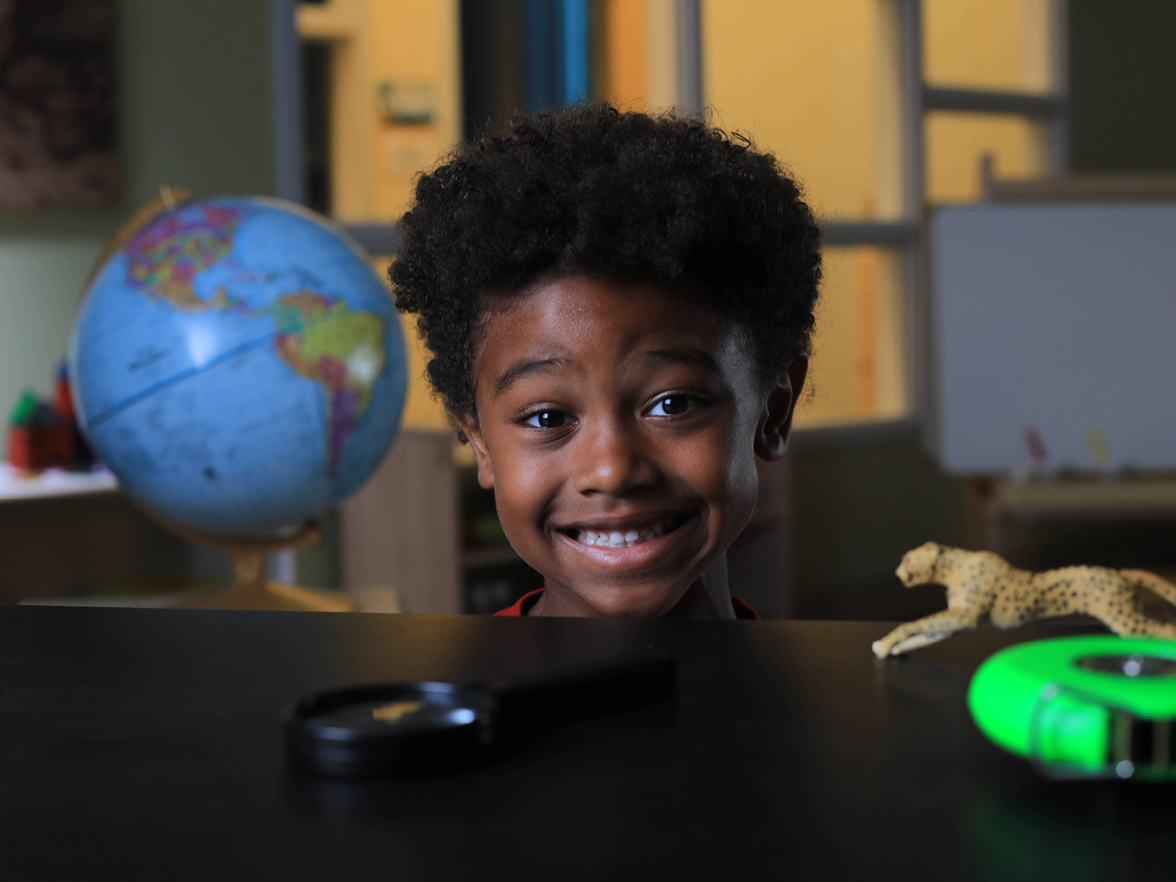 child smiling behind desk