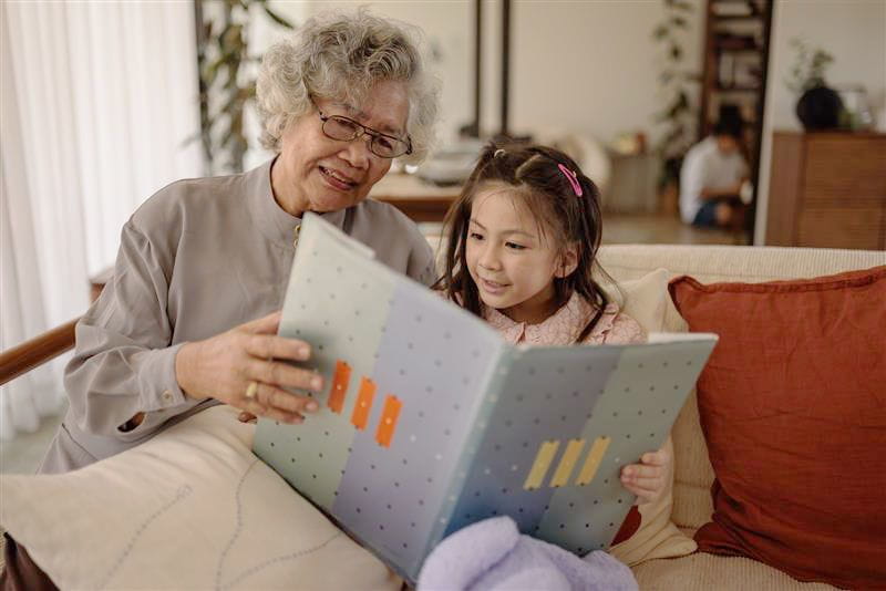 Grandmother and granddaughter reading a book on the couch