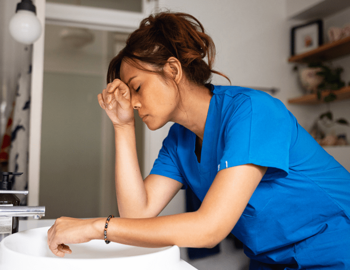 A nurse hunched over a sink