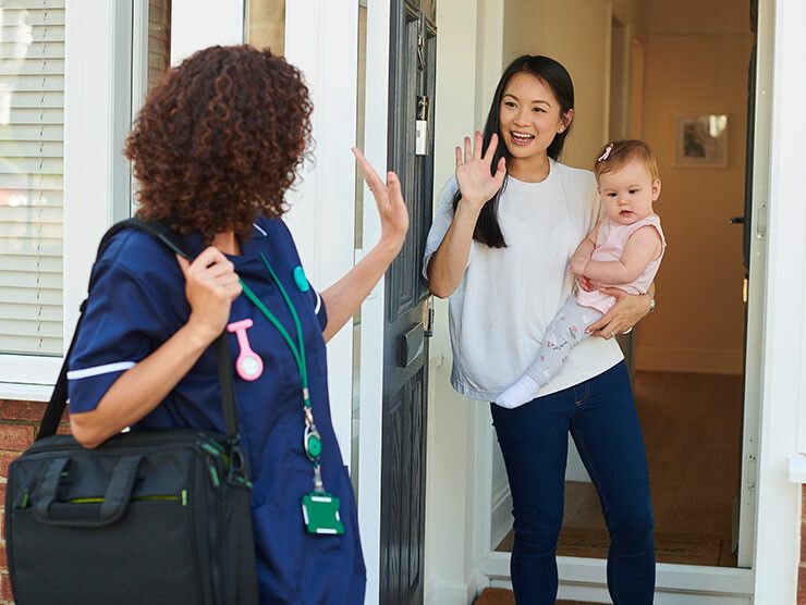 A nurse waving goodbye to a mother and baby
