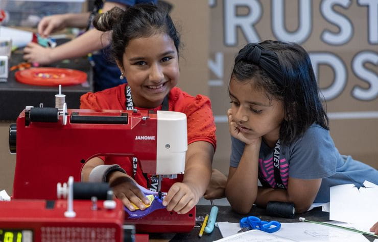 School age girls working with a sewing machine