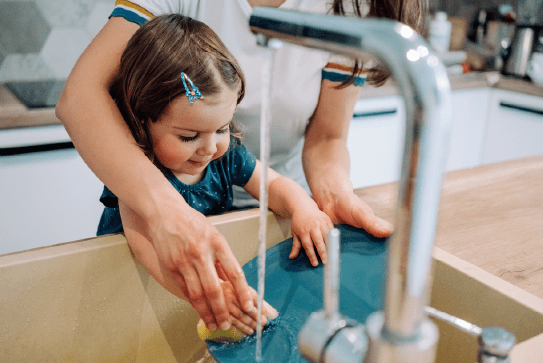 Young girl learning how to wash the dishes