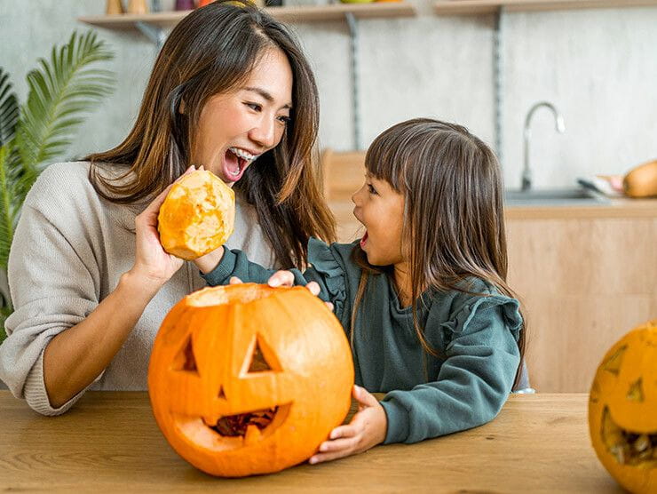 Mother and daughter carving pumpkins in the kitchen